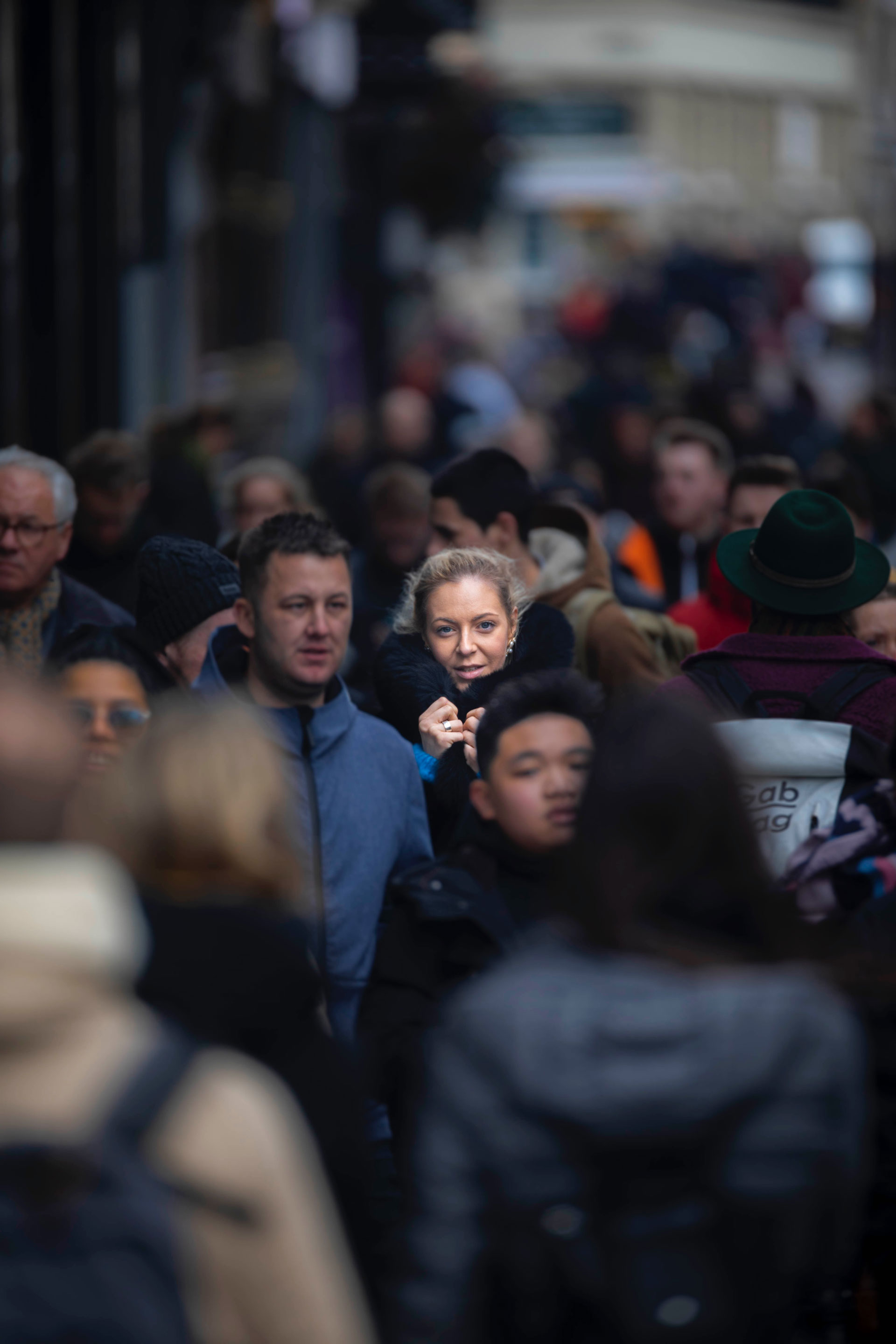 A woman skillfully navigating through a bustling crowd, intently answering her phone as she explores the power of niche marketing for her business.